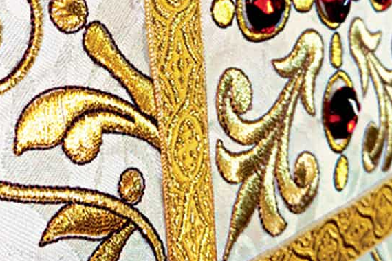 Ricamo sacro dorato su una casula liturgica bianca